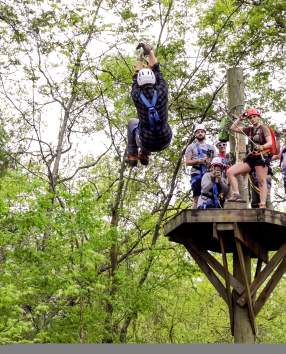 Young man ziplining through trees