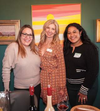 Three women standing close together and smiling