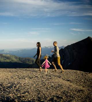 A happy family hiking on top of a mountain with ski trail sign markings