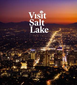 Sunset overhead view of the Salt Lake Skyline with the words Visit Salt Lake and Meeting Planner's Guide Book