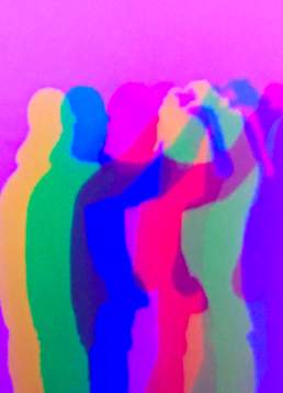 Two people posing in front of a pink screen casting colourful shadows on the wall