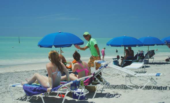 Photo of Mark Timchula "The Beach Guy" delivering a rental chair to beach goers.