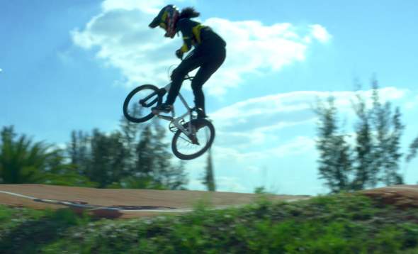 Photo of Amanda Carr on BMX bike, airborne off a jump on the track