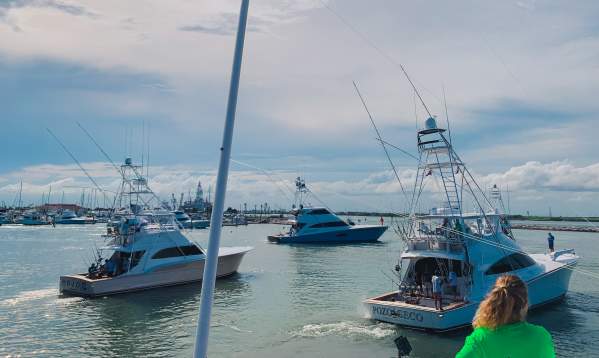 Three boats in a marina. A girl in a green shirt faces away from the camera in the bottom right.