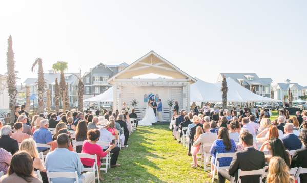 Photo of a crowd watching a couple say vows at outdoor wedding
