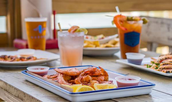 A plate of seafood on a table outside on a deck overlooking the water.