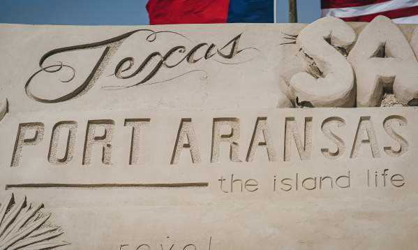 Close-up of a sand sculpture that has "Port Aransas the Island Life" carved into it.