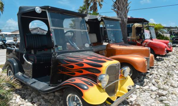 Row of golf carts designed to look like old-times cars painted with flames