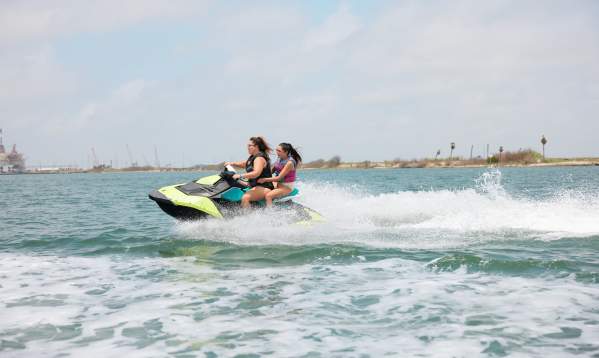 Woman and girl ride on a green jet ski