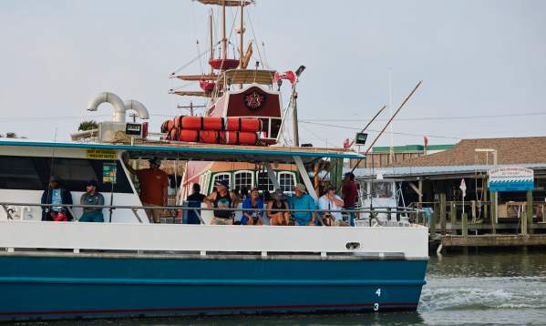 A group sits on a charter boat. Pirate ship is visible in background.