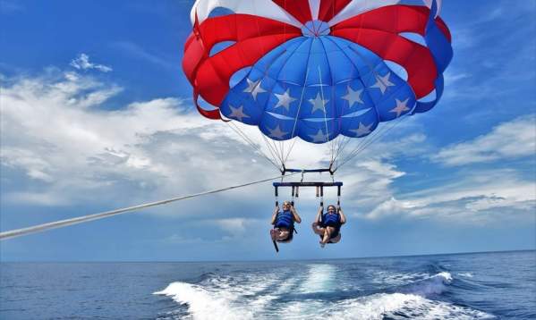 Two people being pulled above the water by a star-spangled parasail