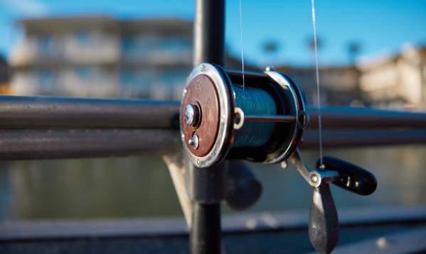 A close up of a silver fishing reel. Background is blurred.