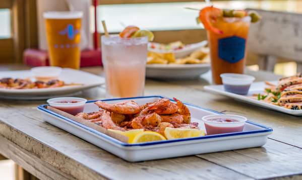 A plate of seafood on a table outside on a deck overlooking the water.