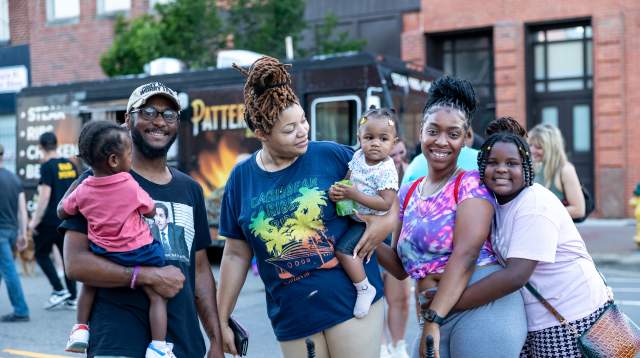 African-American family with three children, parents, and grandmother smiling at local festival