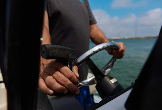 A close up of two weathered hands driving a boat