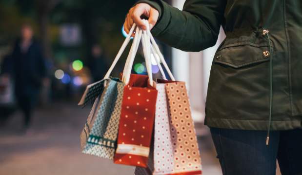 Picture of person holding shopping bags with downtown street view in background.