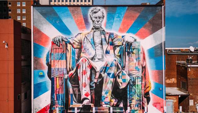 A large mural of Abe Lincoln sitting painted in brightly colored patterns primarily with red, blue, and white.