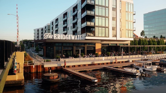 Waterfront view of The Bridgewater restaurant and apartments in Milwaukee, with outdoor dining and boats docked along the river