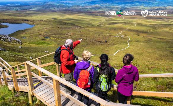 Group of walkers looking out over the landscape from the boardwalk at Cuilcagh Mountain.