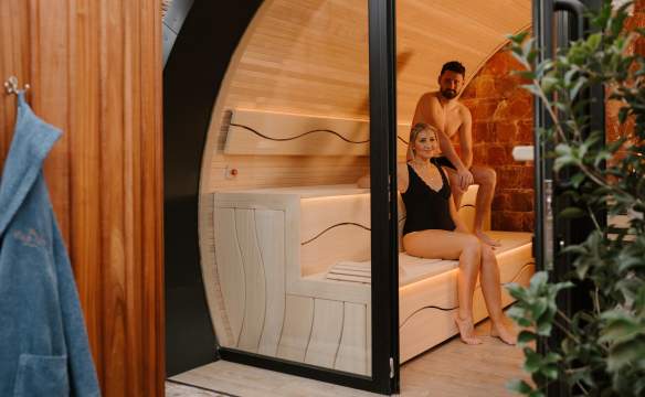 Couple sit in a sauna pod as part of a spa day experience