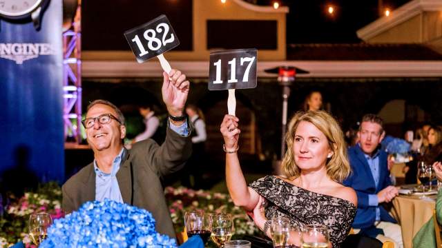 image of two people raising a sign at an auction