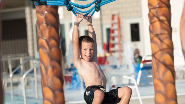 Kid swinging along the floating path at Freedom Springs Greenwood Aquatics Park in Johnson County