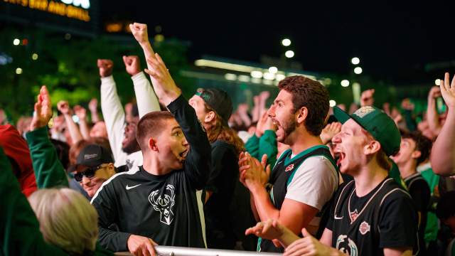 fans in a crowd cheering for the Bucks in playoffs at the Deer District