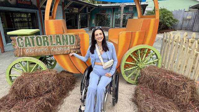 Accesibility influencer Amanda Perla poses in her wheelchair in front of a large pumpkin carriage at Gatorland Orlando