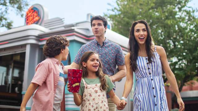A family walking and sharing popcorn in a theme park.
