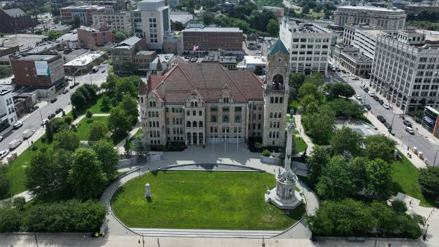 Aerial of a city square with a large courthouse with grass in front