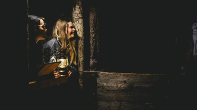 Two people with a lantern looking at a cave wall in the Nanaimo Museum.