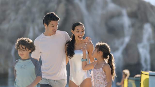 Uma família caminhando pela praia de Volcano Bay no Universal Orlando Resort.