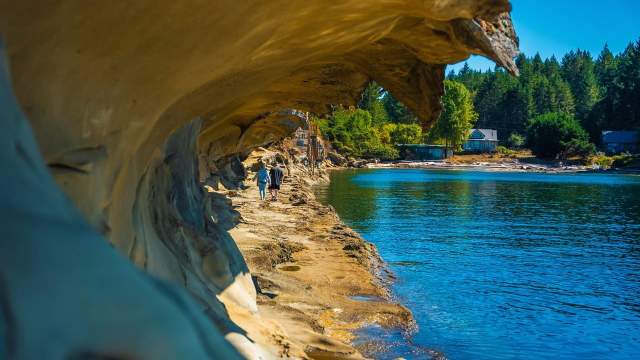 Arched sandstone cliffs by the water.