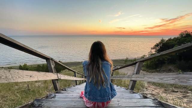 Woman sits on the dune staircase at Laketown Beach