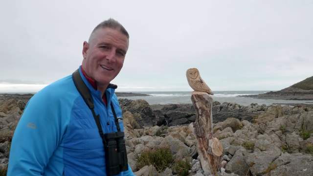 Iolo Williams standing next to a wooden owl.