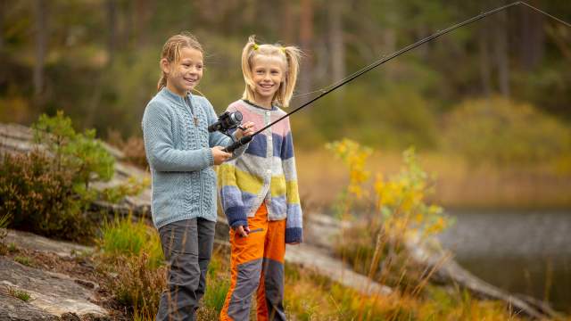 To jenter som fisker ved et vann