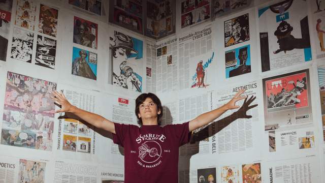 a man in front of a wall of newspapers.
