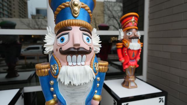 A classic nutcracker statue in a blue uniform with another nutcracker in red in the background