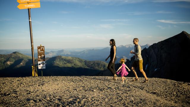 A happy family hiking on top of a mountain with ski trail sign markings