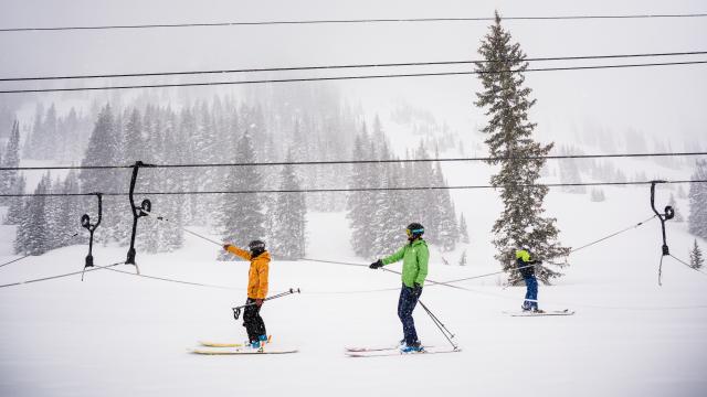 Two skiers on Alta's rope tow with chairlift lines in the background