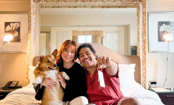 Couple with dog on hotel bed