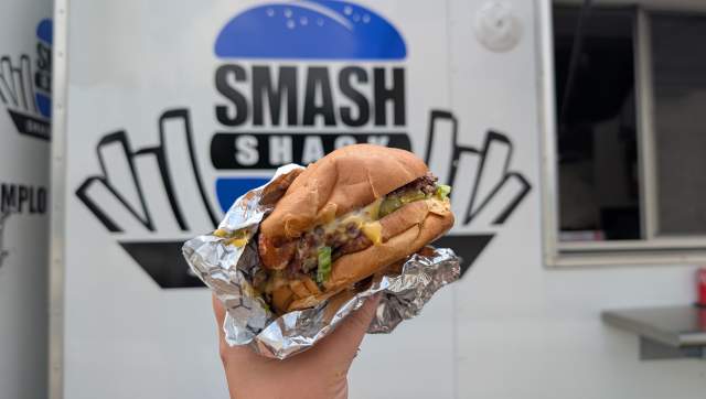 Close-up of a Smash Burger in front of the Smash Shack food truck.