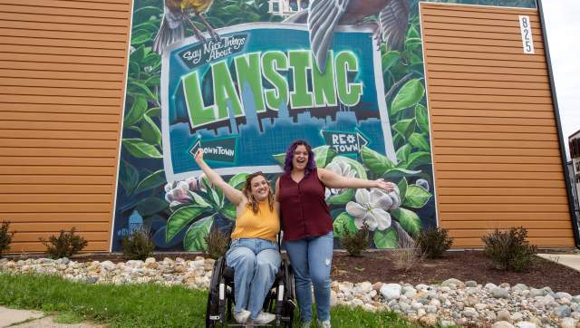 Two ladies in front of a "Say Something Nice Mural Lansing"