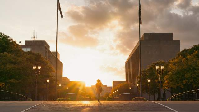 Woman walking across the street with the sun flare behidn her.
