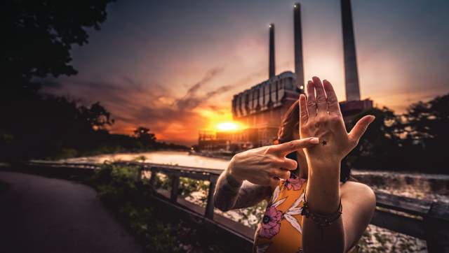 Woman pointing to a star on her hand in front of the Lansing smoke stacks