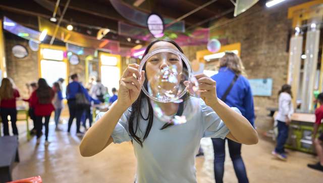 Girl bubbling bubbles through a ring at Impression 5 Science Center