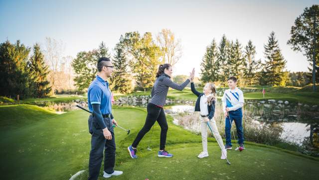 Women and kid high five on a golf course