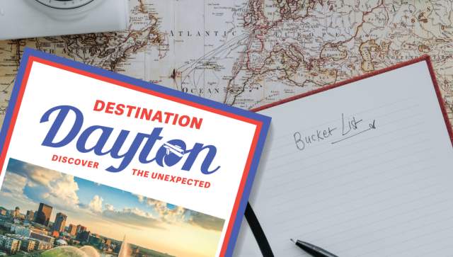 a graphic showing the Destination Dayton Visitors Guide, along with a map, camera, sunglasses and "to do" list