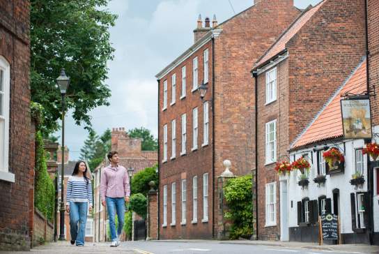 Two people walking along the street in Louth with a traditional country pub in the background