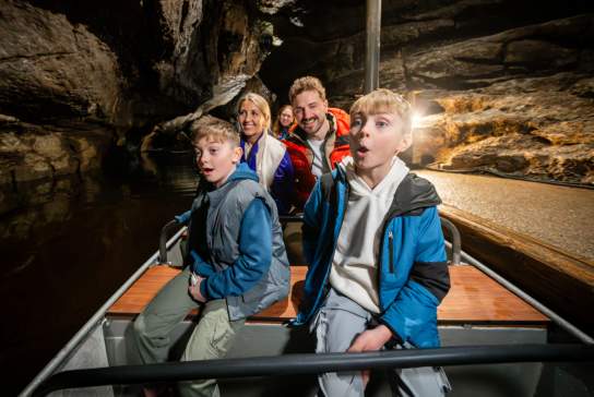 Visitors travelling by boat through the Marble Arch Caves, surrounded by towering limestone formations deep beneath the Fermanagh countryside.